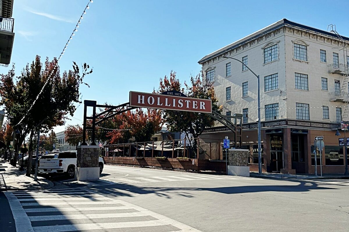 Sign that says Hollister arches over street at intersection of San Benito Street and Fifth Street in Hollister, California.